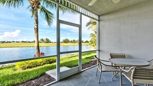 A covered patio with a view of a lake and palm trees.