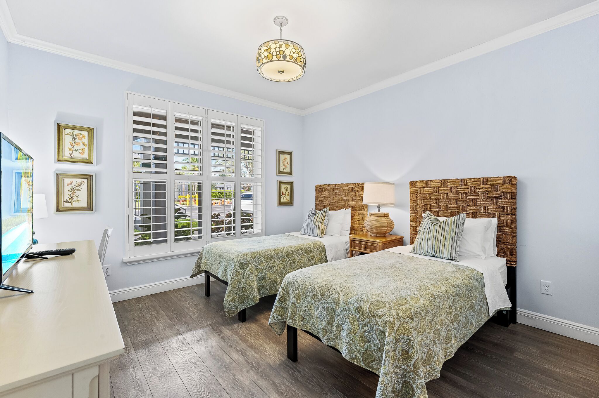 Habitación de hotel con dos camas, un escritorio y un ventanal grande con contraventanas.