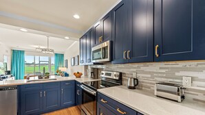 Una cocina moderna con armarios azul oscuro, electrodomésticos de acero inoxidable y una isla grande con pileta y encimera.