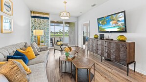 A modern living room with a grey sofa, a coffee table, and a TV on a wooden cabinet. - Solterra Vacation Rental: Luxury 3-BR Condo with Lake & Golf Views. Access to Luxury Pool, Hot Tub, and Golf Courses at Lely Resort. Close to Naples Beaches, 5th Avenue S, and Marco Island (Naples)