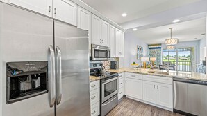 A modern kitchen with stainless steel appliances, white cabinetry, and a built-in water dispenser. - Solterra Vacation Rental: Luxury 3-BR Condo with Lake & Golf Views. Access to Luxury Pool, Hot Tub, and Golf Courses at Lely Resort. Close to Naples Beaches, 5th Avenue S, and Marco Island (Naples)