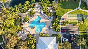 An aerial view of a resort with a central pool, lounge areas, and a parking lot. - Solterra Vacation Rental: Luxury 3-BR Condo with Lake & Golf Views. Access to Luxury Pool, Hot Tub, and Golf Courses at Lely Resort. Close to Naples Beaches, 5th Avenue S, and Marco Island (Naples)