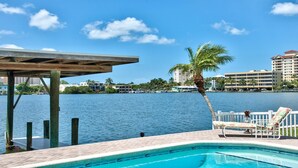 A swimming pool with a view of a body of water and buildings in the background. - Canal Grande Waterfront 6 Bedroom Holiday Home by Naples Florida (Naples)