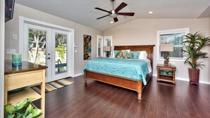 A bedroom with a bed, a desk, a ceiling fan, and a window.