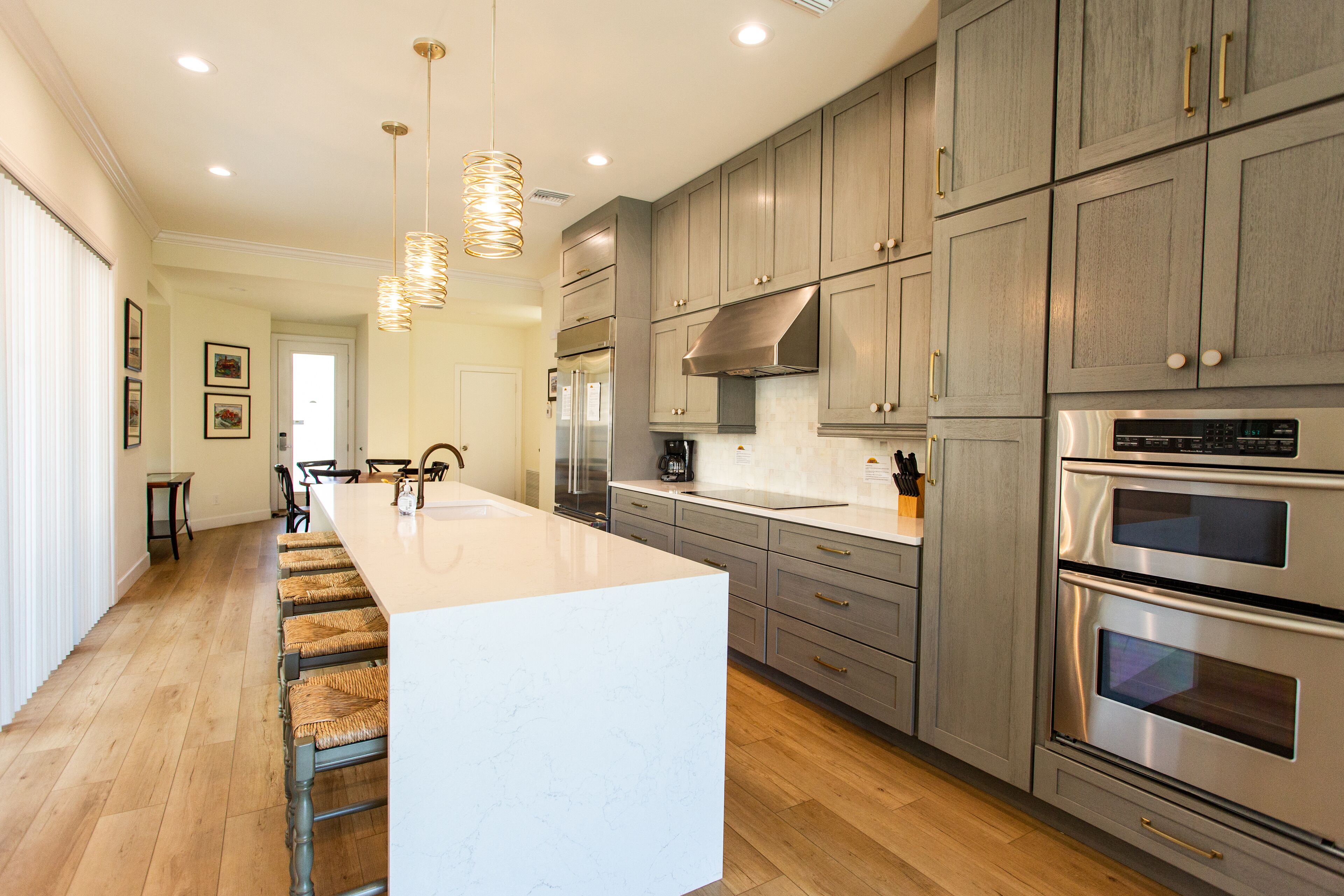 A modern kitchen with a large island, stainless steel appliances, and wooden flooring.
