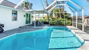 A covered swimming pool with a patio area, a table, and chairs. - Tuscan Vacation Rental. Stylish 3-Bedroom Getaway Near Vanderbilt Beach Enjoy a Private Pool, Spacious Layout, and Modern Comforts Perfect for Families, Groups, and Pet-Friendly Stays (Naples)