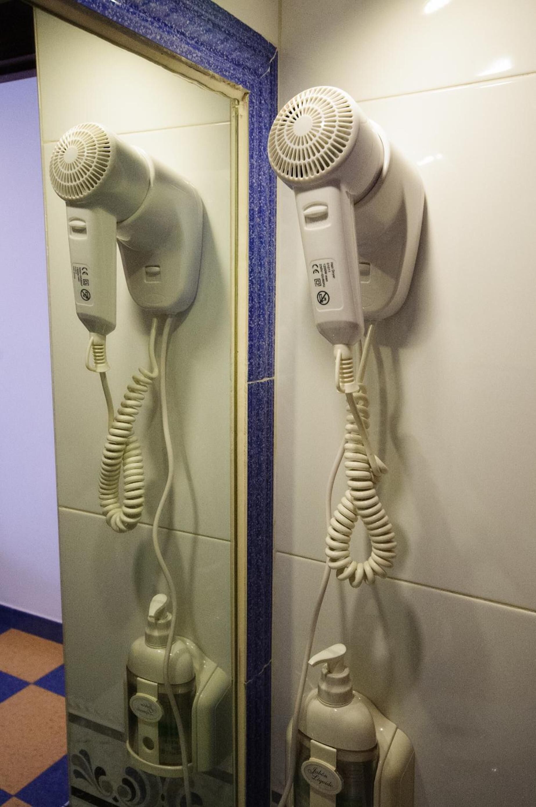 Dois secadores de cabelo fixados numa parede com uma moldura azul.