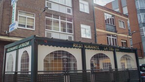 Un edificio de varios pisos con un restaurante llamado 'Restaurante La Trucha' en la planta baja.