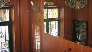 Interior de madera con una araña, un espejo que refleja una puerta y un letrero que dice "SALIDA".
