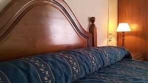 Una cama con cabecera de madera y colcha azul estampada.