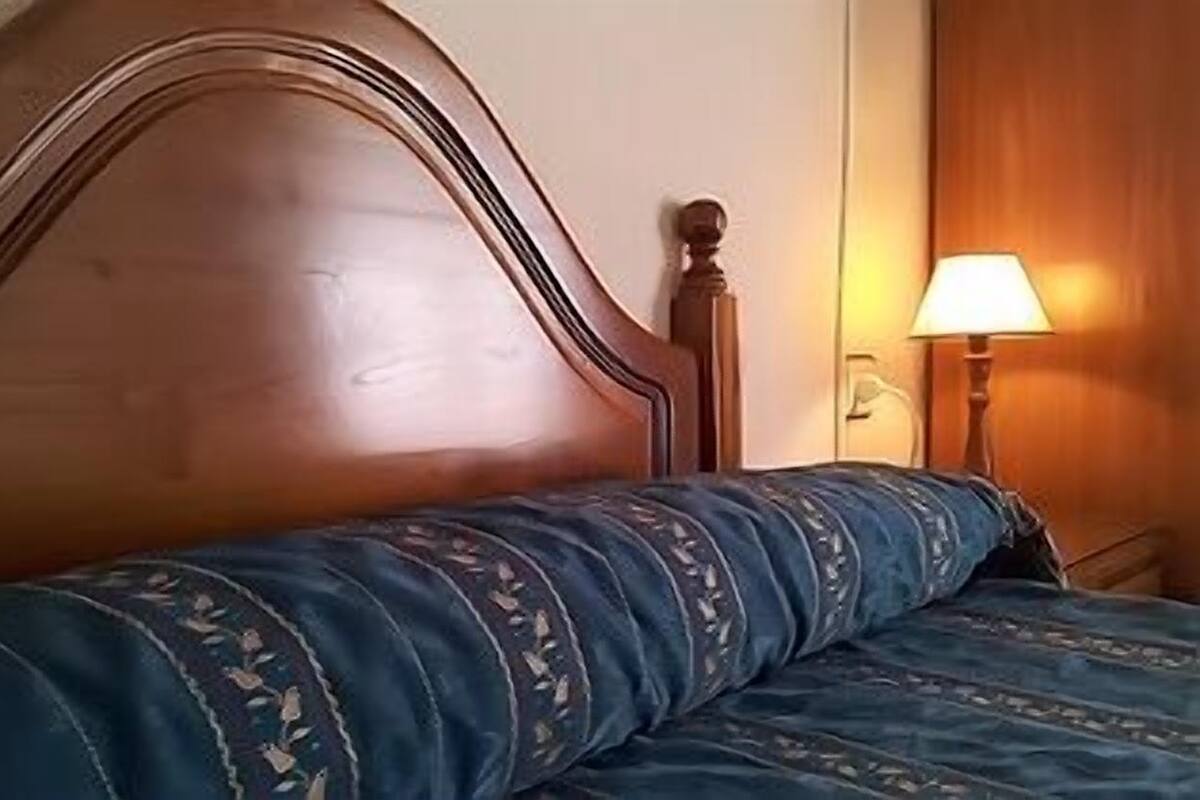 A bed with a wooden headboard and a blue patterned bedspread.