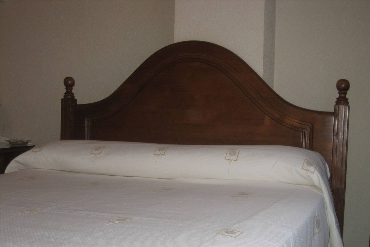 A neatly made bed with a wooden headboard and a white bedspread.