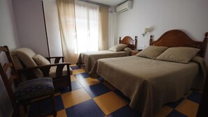 Habitación de hotel con dos camas, una silla, una mesita de noche y una ventana con cortinas.