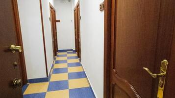 Un pasillo con suelo a cuadros azul y amarillo, puertas de madera y techo blanco.
