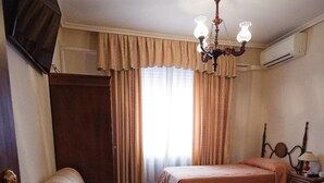 Habitación de hotel con dos camas, un sofá, una mesita y un televisor.