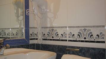 A bathroom with a white sink, a hairdryer, and a towel rack.
