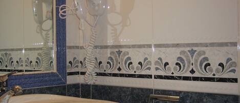 A bathroom with a white sink, a hairdryer, and a towel rack.