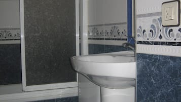 A bathroom with a toilet, sink, and a window.