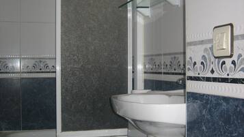 Ein Badezimmer mit Toilette, Waschbecken und Duschbereich.