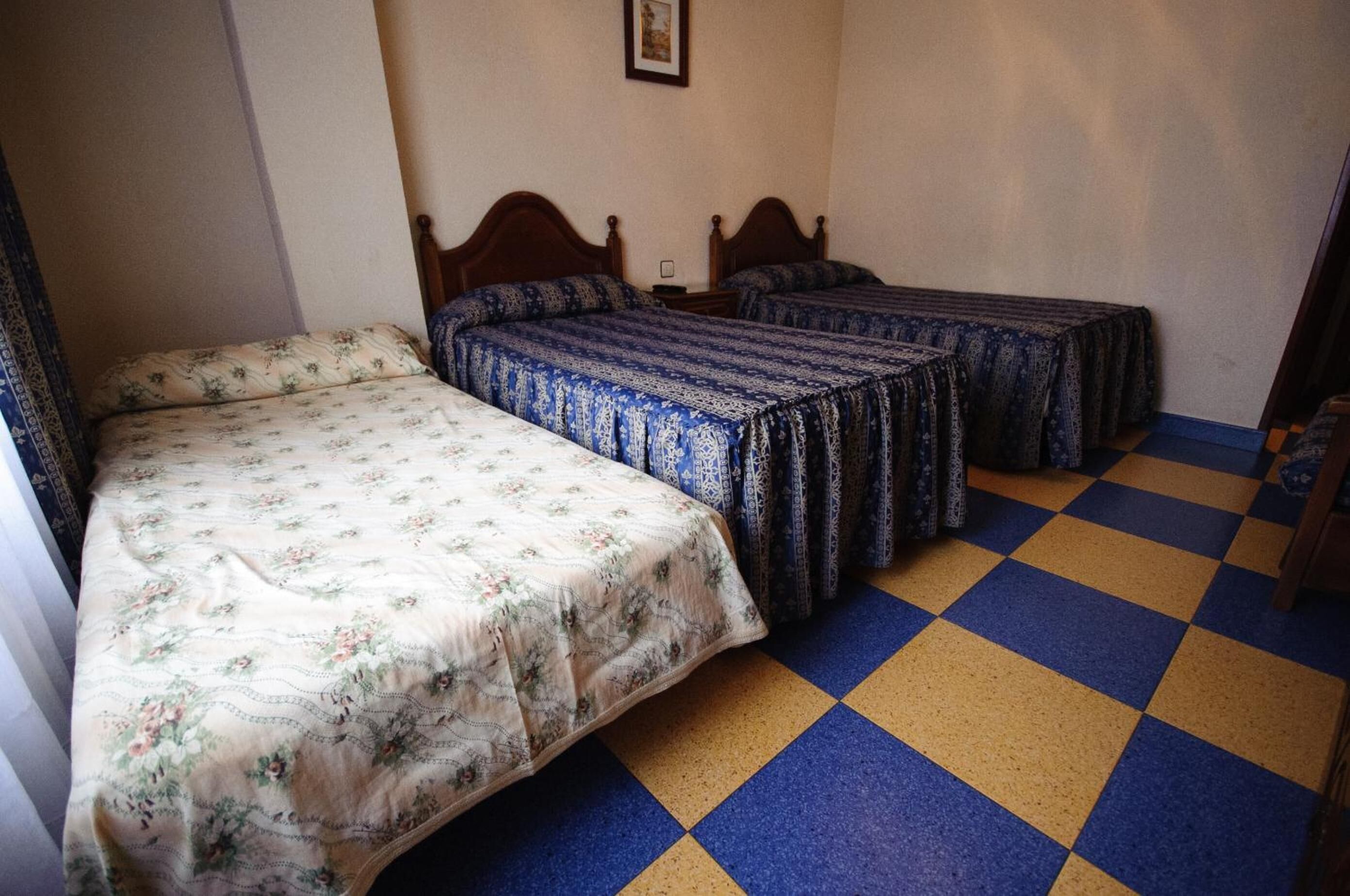 Um quarto com duas camas, piso xadrez e um quadro na parede.