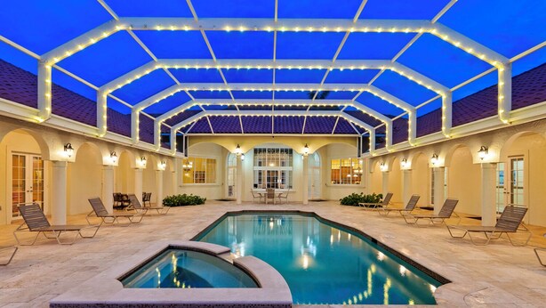 An indoor swimming pool with a glass ceiling, lounge chairs, and a patio area. - Knickerbocker Estate: Elegant 9-BR Getaway in Naples. Enjoy Private Pool, Outdoor Dining, and Expansive Grounds, Experience Tranquility with Easy Access to Naples' Best (Naples)