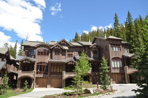 A large, multi-story wooden house with a stone facade, multiple windows, and a driveway leading to the entrance. - Base Camp 480 4 Bedroom Holiday Home by Winter Park Lodging Company (Winter Park)