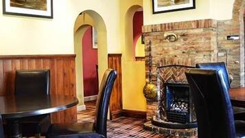 A restaurant with a stone fireplace, wooden booths, and a checkered floor.