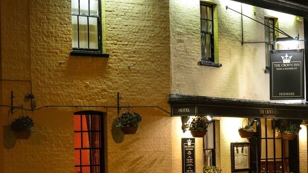 A building with a sign reading "The Crown Inn Hotel & Restaurant" and "Freehouse." There are windows with plants hanging outside, and a signboard with the inn's name and services. - The Crown Hotel (Sudbury)