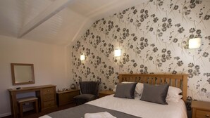 A bedroom with a bed, bedside tables, a chair, a desk, and a mirror. - The Crown Hotel (Sudbury)