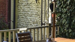 A wooden table with a bench, a metal railing, and a stone wall in the background. - The Crown Hotel (Sudbury)