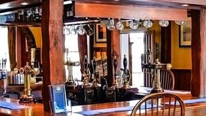 A bar area with wooden counter and brass fixtures, including taps and a beer tap. - The Crown Hotel (Sudbury)