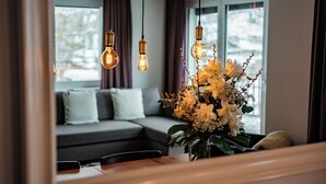 Een knus vertrek met een houten tafel, een decoratieve bloemstelling en drie hangende lampen.