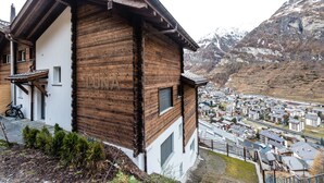 Een houten chalet met een balkon, met uitzicht op een stad en bergen.