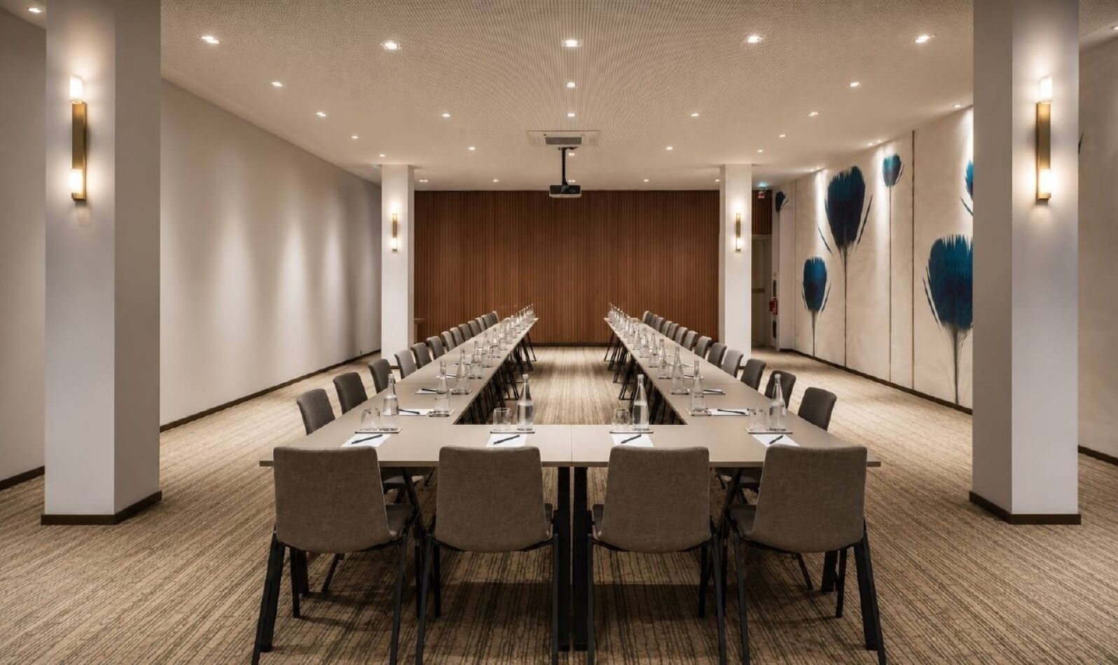A conference room with a long table, chairs, and a wooden panel wall.