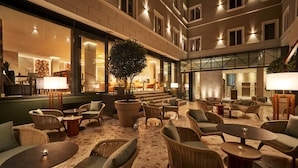A spacious outdoor seating area with wicker furniture and a tiled floor, overlooking a building with large windows and a staircase. - Radisson Hotel City Centre Odesa (Odesa)