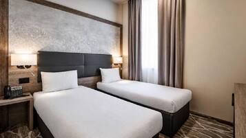 A hotel room with two beds, a large wall art piece, a telephone, and a window with curtains.