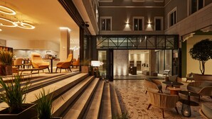 A hotel lobby with a modern design, featuring a spacious seating area with sofas and chairs, a staircase leading to the upper floor, and a glass entrance to the rooms. - Radisson Hotel City Centre Odesa (Odesa)
