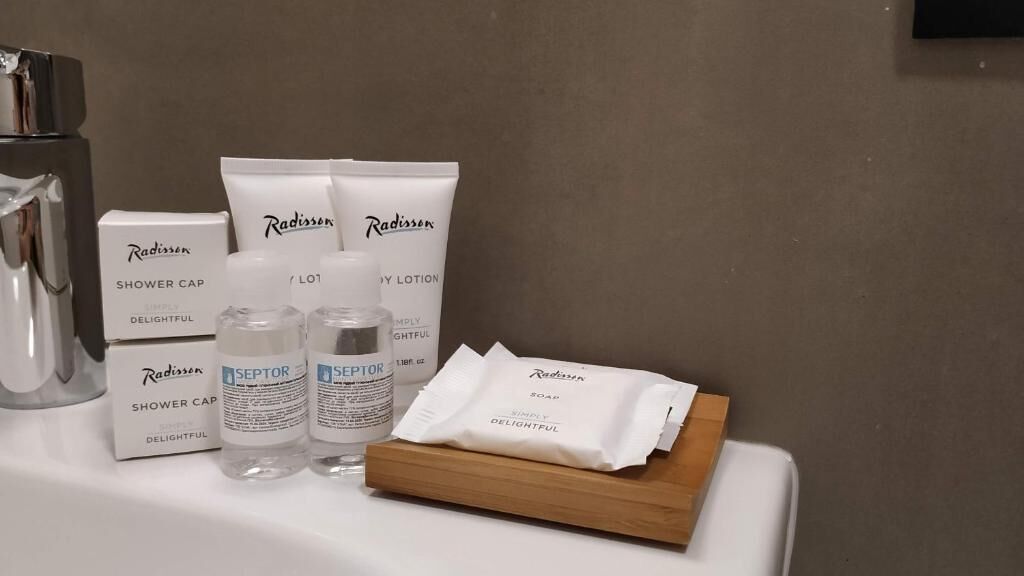 Et badeværelse med en hårbånd, lotion og sæbe på en bordplade.