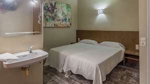 A bedroom with a wooden headboard, a white bed, a bedside table, a white sink, and a mirror. - Hostal Sant Miquel (Balaguer)