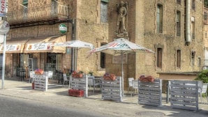 A stone building with outdoor seating and a statue. - Hostal Sant Miquel (Balaguer)