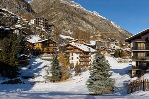 A snow-covered mountain resort with wooden buildings and a ski slope. - Haus Haro by Zermatt Premium Apartments (Zermatt)