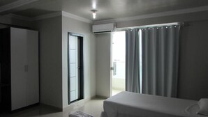 Habitación de hotel con cama, armario, puerta y ventana con cortinas.