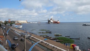 Un paisaje urbano costero con un puente destacado, barcos y un paseo marítimo.