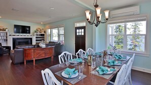A dining area with a wooden table set for six, white chairs, and a chandelier. - The Lookout at Cranes Landing (Greenbank)