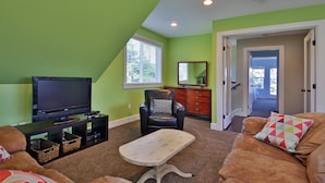 A living room with a television, a leather chair, a sofa, and a coffee table. - The Lookout at Cranes Landing (Greenbank)