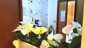 A reception area with a desk, a bulletin board, and a mirror reflecting the room. - B&B Piazza Ragusa (Rome)