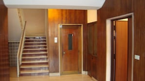 A wooden interior hallway with a staircase, a door, and a wall-mounted light fixture. - B&B Piazza Ragusa (Rome)