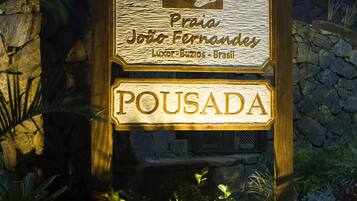 Une enseigne en bois portant les mots « Pousada » et « João Fernandes », indiquant un établissement proposant des hébergements.