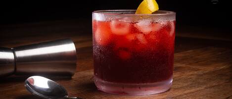 A cocktail glass with a lemon garnish on a wooden surface.