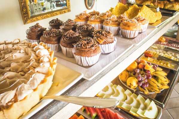 A buffet with various food items including cupcakes, pastries, and fruits. - Pousada Praia João Fernandes (Búzios)